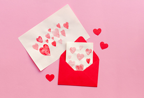 Envelope with heart-shaped design beside a pink card