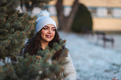 Beautiful young woman by a tree in nature during winter.