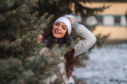 Beautiful young woman by a tree in nature during winter.