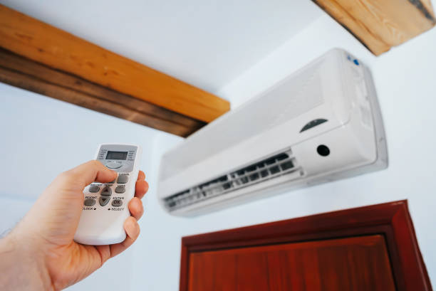 istock Hand holding remote control in front of the air conditioner. 1942998368