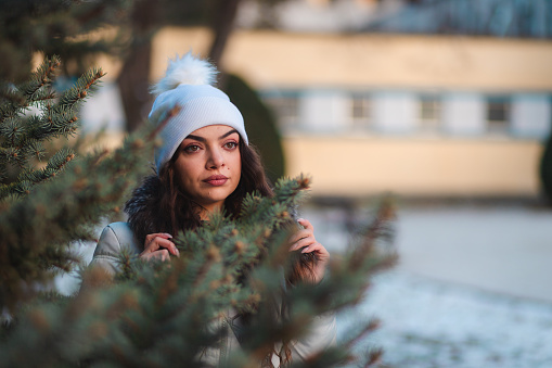 Beautiful young woman by a tree in nature during winter.