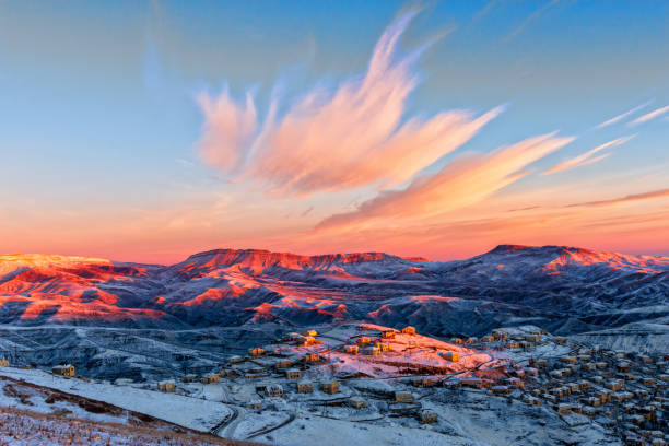Morning dawn over the village of Kubachi in Dagestan Caucasus Mountains in Dagestan, the famous village of Kubachi, winter morning dawn. Some of the mountains and houses are brightly illuminated by the rays of the rising sun, the other part is in the predawn twilight. In the sky, bright cirrus clouds in the form of a crown create a beautiful skyscape. caucasus stock pictures, royalty-free photos & images