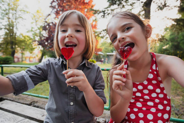 幸せな小さな男の子と女の子とロリポップが楽しんで自分撮りをする - child valentines day candy eating ストックフォトと画像