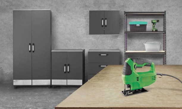Electric jigsaw  on a wood working table in a garage with cabinets
