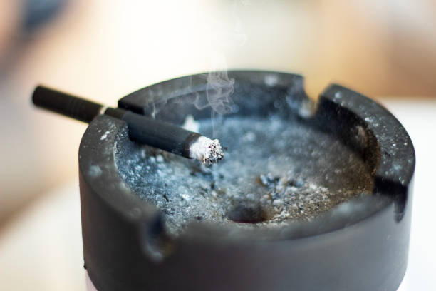 istock Cigarette with smoke in black astray. Ashes and butts on astray 1943060047