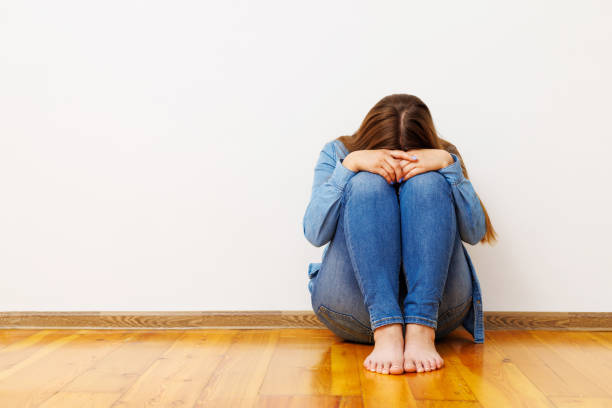 istock Distressed Woman Sitting on Floor Against Wall 1943060055