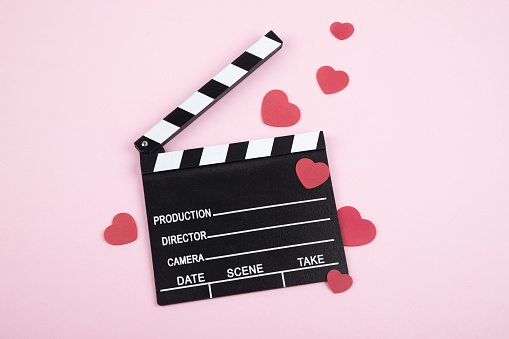 Movie clapper board with hearts isolated on pink background