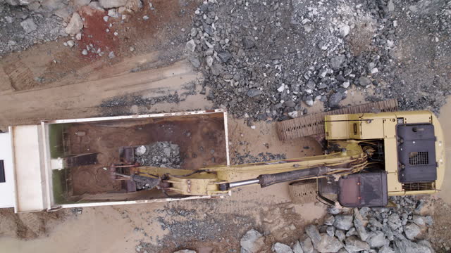 A dynamic drone shot of a excavator which empties its yield into a mining truck