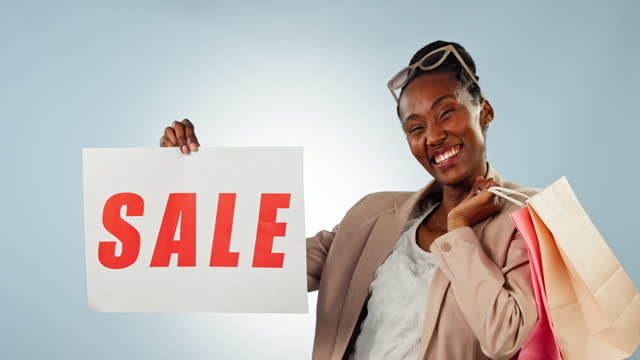 Happy black woman, sale sign and shopping bag for discount, deal or promotion against a studio background. Portrait of African female person or shopper smile with billboard, poster or store promo