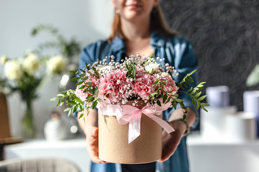 Beautiful woman florist standing and holding bouquet of flowers in flower shop