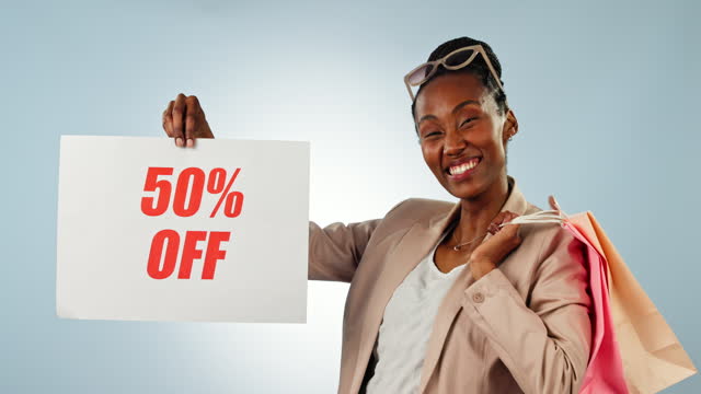 Black woman, discount and billboard sign with shopping bag for deal, sale or promotion against a studio background. Portrait of happy African female person or shopper smile with poster on store promo