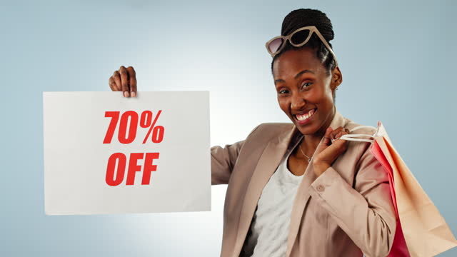 Happy black woman, discount sign and shopping bag for deal off, sale or promotion against a studio background. Portrait of African female person or shopper smile with billboard, poster or store promo