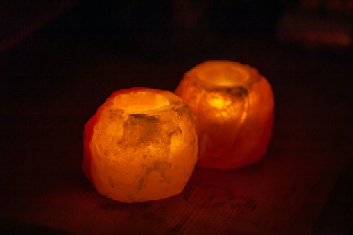 Candlesticks for tea lights made of salt with a dark background.