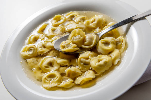istock Soup bowl with tortellini in broth with spoon 1943135378