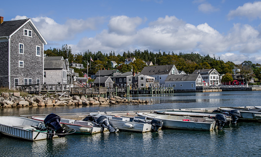 Small fishing boats, some with lobster holding boxes, wait at a pier in Stonington, Maine.