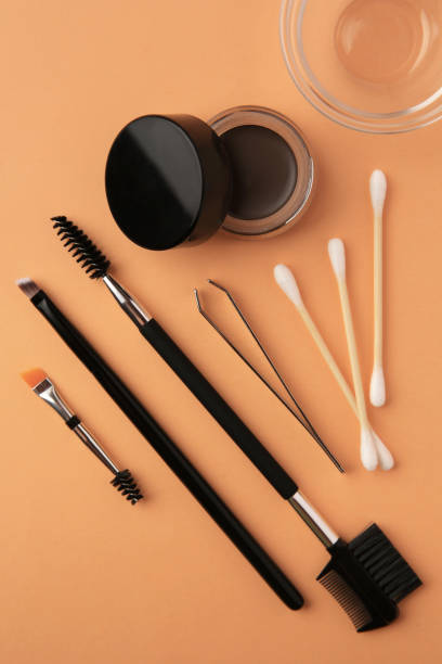 istock Eyebrow pomade with henna effect and professional tools on orange background, flat lay 1943149925