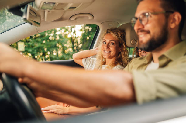 istock Mother sitting on a passenger seat looking at her husband while driving children 1943151501