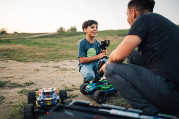 istock Boy talking to his father during playtime with two remote controlled car toys 1943152541