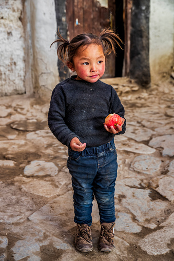 Portrait of Tibetan little girl eating an apple, Lo Manthang, Upper Mustang. Mustang region is the former Kingdom of Lo and now part of Nepal,  in the north-central part of that country, bordering the People's Republic of China on the Tibetan plateau between the Nepalese provinces of Dolpo and Manang.