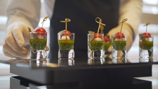 Catering. The waiter lays out snacks. off-premise catering - waitresses put fruit canapes on buffet table