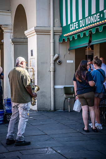 New Orleans, LA - October 18, 2023: Saxophonist playing on the sidewalk outside of Cafe Du Monde on Decatur Street.