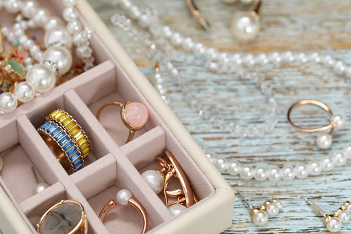 Jewelry box with many different accessories on rustic wooden table, closeup