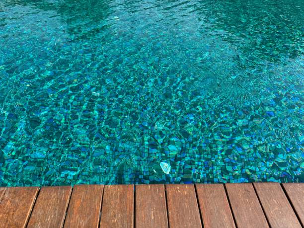 istock Clear rippled water in swimming pool and wooden deck outdoors. Space for text 1943188689