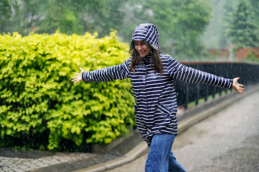 Teenage girl running in the rain with arms outstretched. The girl is enjoying the spring rain.\nShot with Canon R5