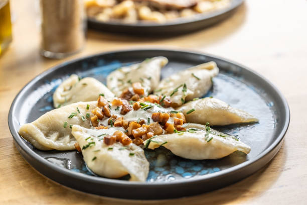 Filled pirohy dish served with fried bacon, fresh chive, and sour cream.
