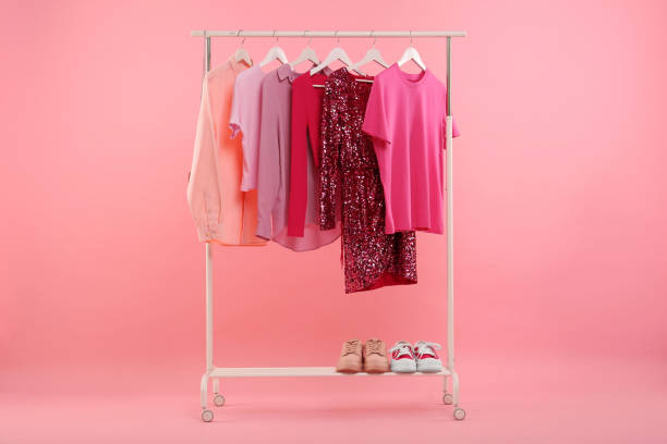 istock Rack with different stylish women`s clothes and sneakers on pink background 1943201759