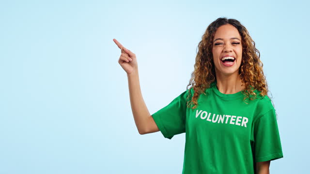Face, woman and volunteer pointing, promotion and announcement on a blue studio background. Portrait, person and activist with hand gesture, help and presentation with opportunity and sustainability
