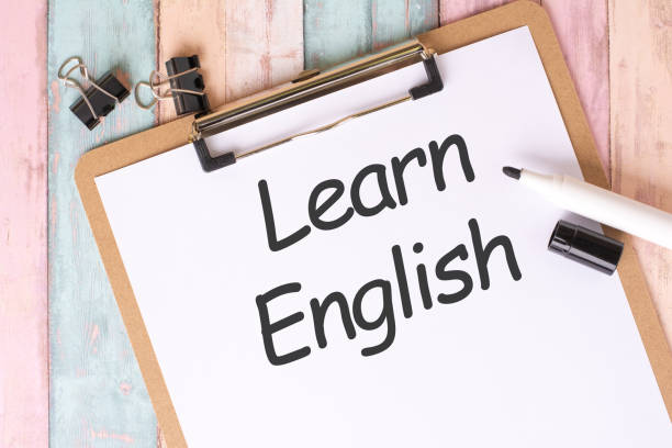 istock Learn English Text written on notebook page, black pencil and coffee cup. Office desk table top view 1943253321