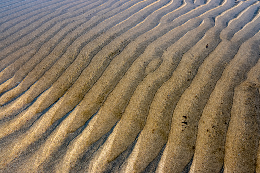 water rills on the shore of a beach during low tide at sunset