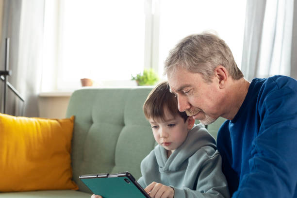 istock A 6 year old boy and his dad are relaxing on the sofa and using digital devices 1943294385