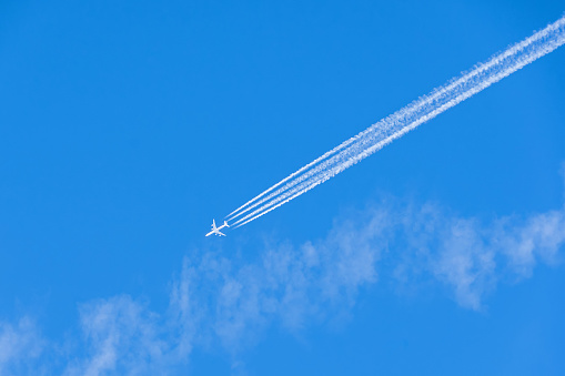 January 2024: White Airplane in the blue sky leaving vapor trail