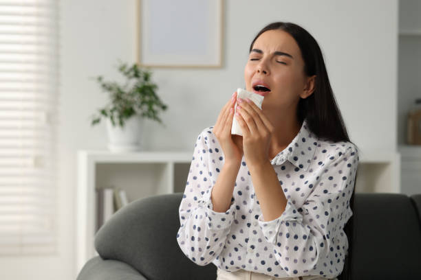 istock Suffering from allergy. Young woman with tissue sneezing at home, space for text 1943301844