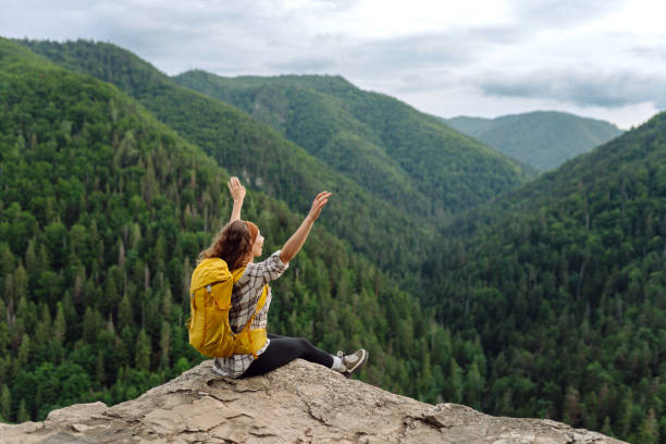 istock Young woman  with backpack on mountain peak looking in beautiful mountain. 1943302945
