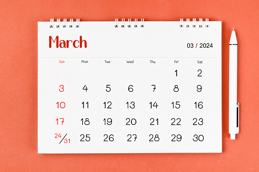 March 2024 Monthly desk calendar for 2024 year and pen on red color background.