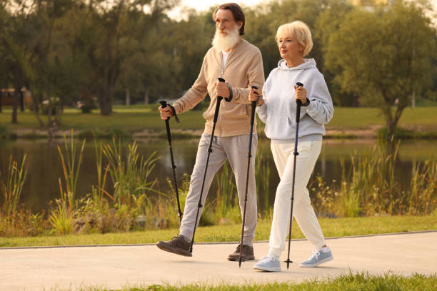 istock Senior man and woman performing Nordic walking outdoors, space for text 1943396888