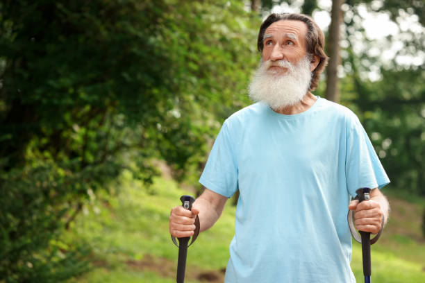 istock Senior man with Nordic walking poles outdoors, space for text 1943400405