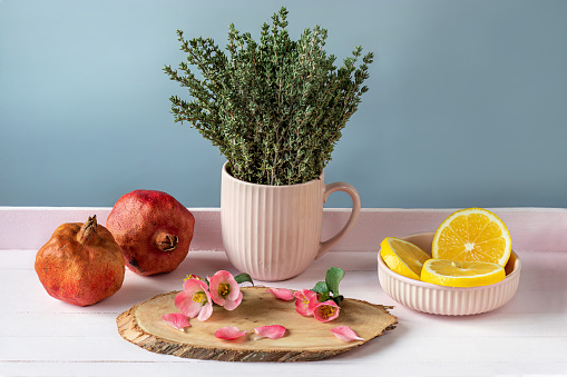 Thyme, lemon, pomegranates, flowers Japanese quince on stand made of sawn juniper. Tea party set.