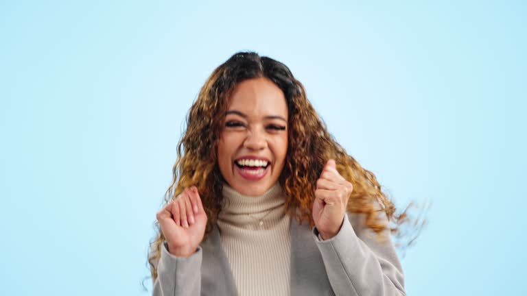 Face, dance and woman with celebration, employee and achievement on a blue studio background. Portrait, happy person and model with energy, winner and excited for professional promotion and award