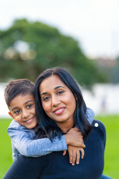 istock Loving mother and son playing piggyback in the park. Both are happy and smiling 1943455607
