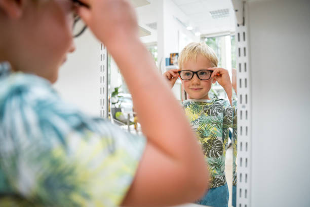 istock Child Stands Before Optician's Mirror with Eyeglasses 1943460788