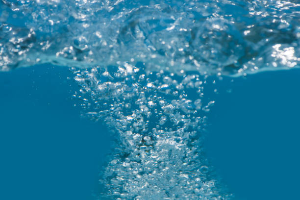 Bluewater waves on the surface ripples blurred. Defocus blurred transparent blue colored clear calm water surface texture with splash and bubbles. Water waves with shining pattern texture background.