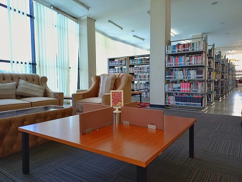 the atmosphere in a public library with bookshelves, sofa, and cross-legged reading tables.
