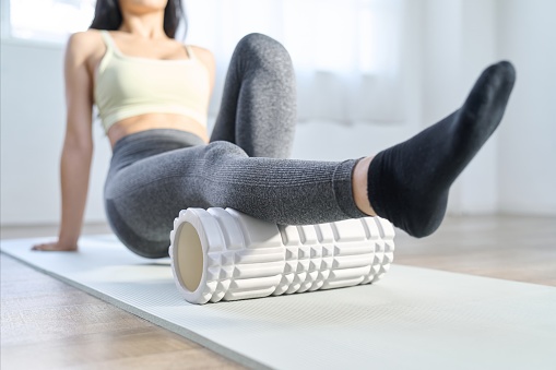 A woman using a foam roller to relax the back of her knees