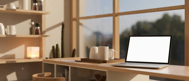 istock A white-screen laptop computer mockup on a kitchen countertop against the window on a sunny day. 1943743590
