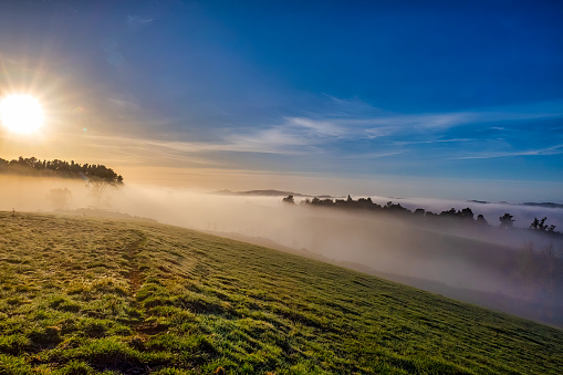 The Rural Hills of Berwick (south west of Dunedin) at sunrise on a freezing frosty day with low mist and fog rolling through the valleys