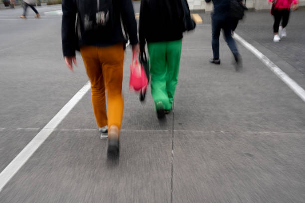Blurred motion photo of two pedestrians wearing bright green and orange pants